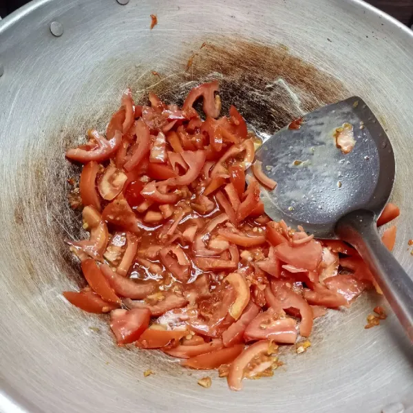 Masukkan irisan tomat, aduk rata. Tumis sampai tomat layu. Bumbui dengan garam dan kaldu bubuk.