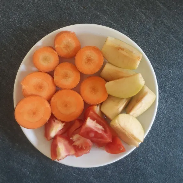 Cuci bersih buah apel, wortel, dan tomat, lalu potong-potong.