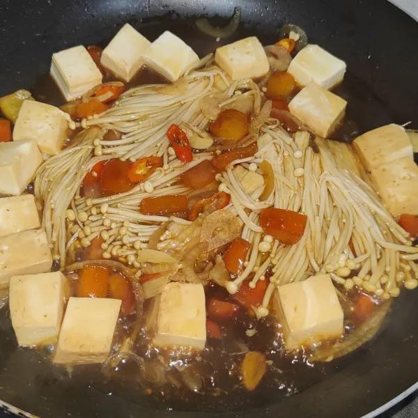 Masukkan jamur enoki dan silken tofu, lalu tuang campuran bumbu saus. Masak hingga mendidih.