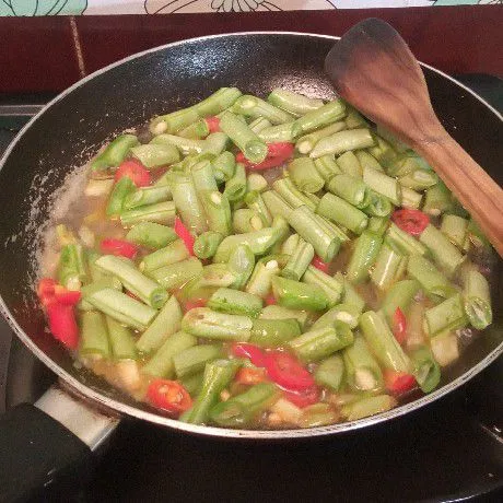 Tuang sedikit air, lalu masukkan buncis dan aduk rata. Masak sampai setengah matang.