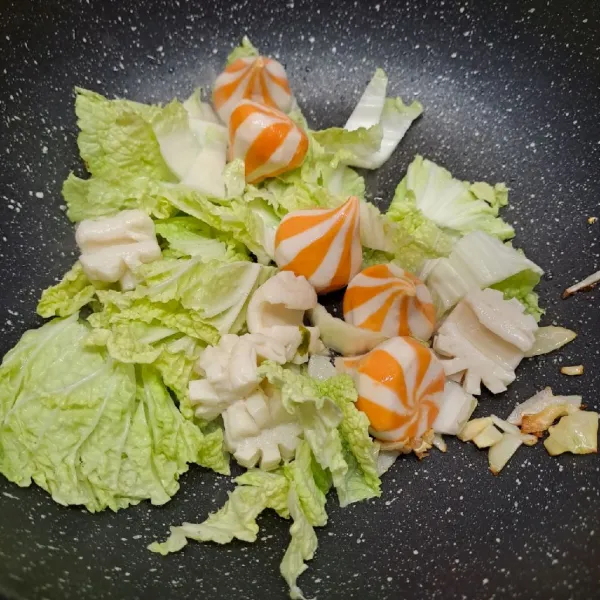 Masukkan sawi putih, squid flower, dan cheese dumpling.  Tumis sebentar dengan bumbu, lalu tuang air dan masak sampai mendidih.