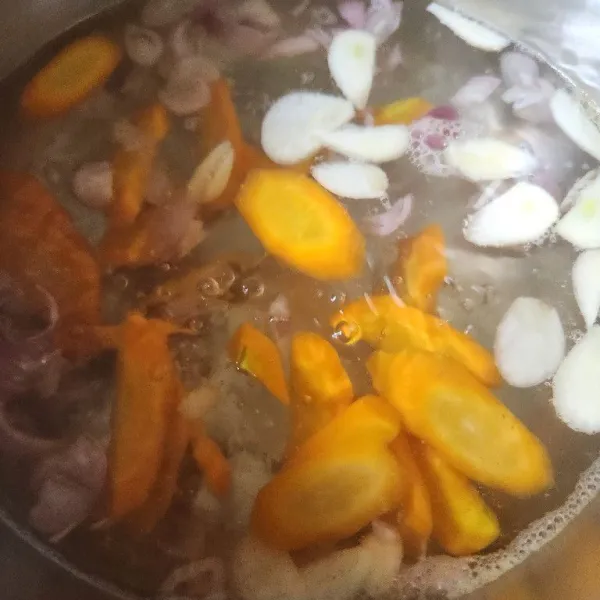 Masak air secukupnya hingga mendidih lalu masukkan wortel, bawang merah, bawang putih.