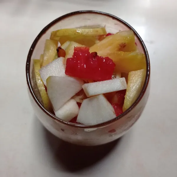 Siapkan gelas saji, masukan es batu, dan buah ke dalam gelas.