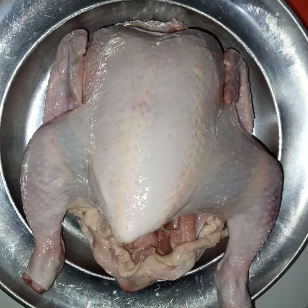 Cuci bersih ayam dengan dikucuri air jeruk nipis. Buka perlahan kulit ayam, dengan cara memasukkan tangan ke dalam ayam antara daging dan kulit, pisahkan dengan cara melepas lemak putih ayam jangan sampai kulit robek.