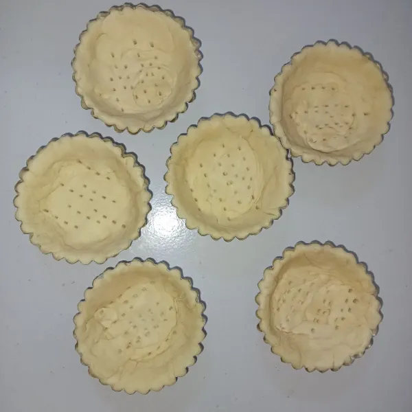 Letakkan kulit pastry di dalam loyang pie yang sudah diolesi dengan margarin, sisihkan.