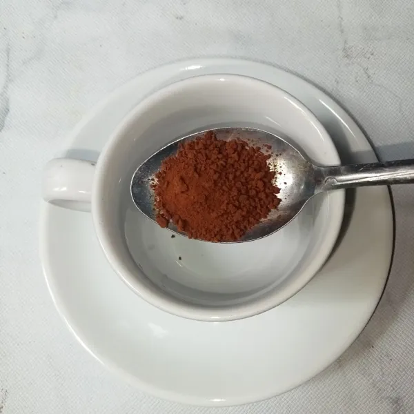 Masukkan kopi bubuk ke dalam cangkir.