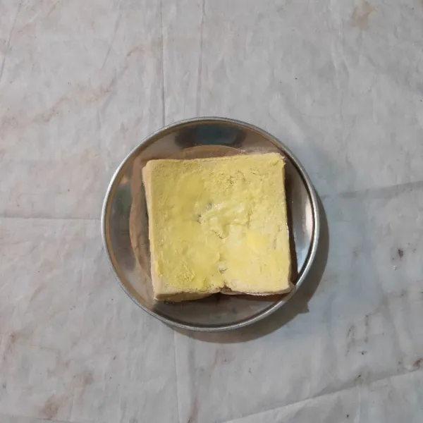 Tumpuk roti menjadi satu. Kemudian oles margarin pada sisi atas dan bawah roti.