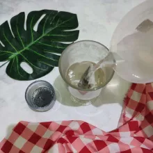 Tuang air panas ke dalam gelas, lalu rendam biji selasih dengan sedikit air panas.