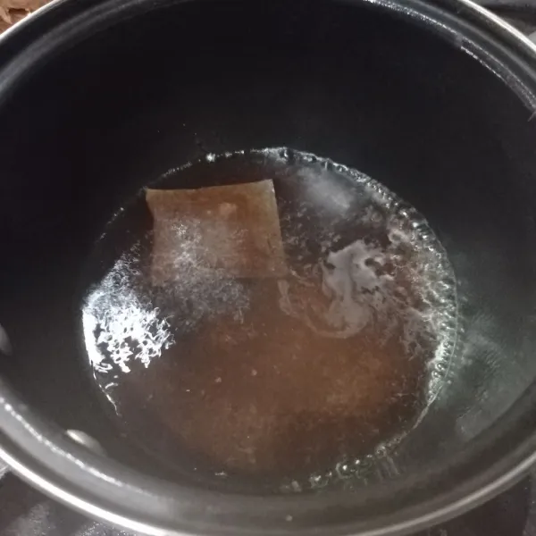 Tuang 150 ml air ke dalam panci, tambahkan gula pasir dan teh celup, nyalakan api dan masak sampai mendidih. Setelah teh berwarna, matikan api dan biarkan hangat.