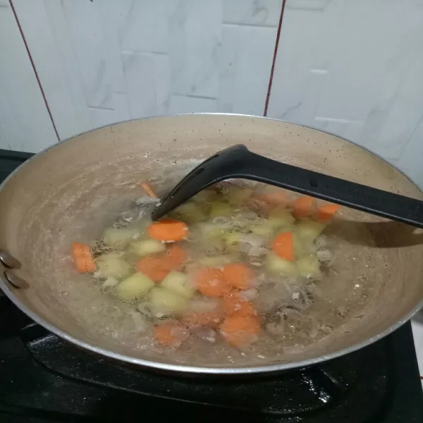 Tambahkan air, masak sampai mendidih lalu masukan kentang dan wortel.