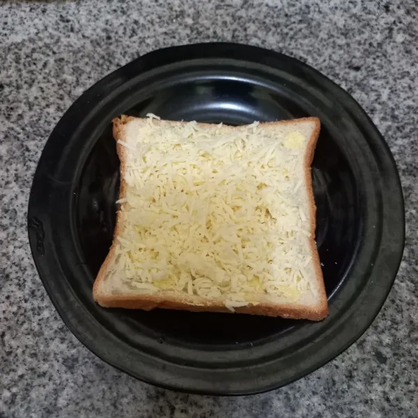 Tambahkan keju parut pada roti.
