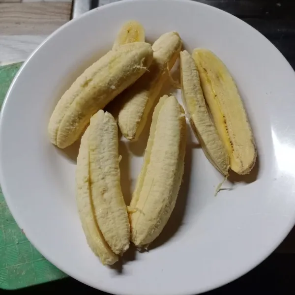 Kupas pisang kemudian belah menjadi 2 bagian.