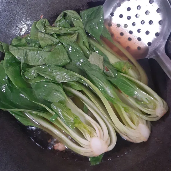 Panaskan minyak sayur, tumis bawang putih hingga kuning, tuangkan air dan kecap asin, aduk rata dan masak hingga mendidih. Masukkan pakcoy, masak hingga ½ layu, angkat dan tiriskan dari air. Sisihkan.