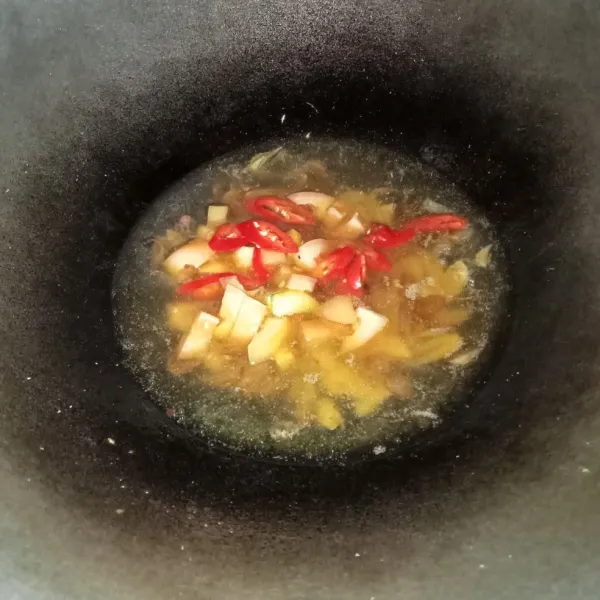 Masukkan irisan tomat dan cabai, aduk-aduk sebentar sampai sedikit layu, lalu tuang air.