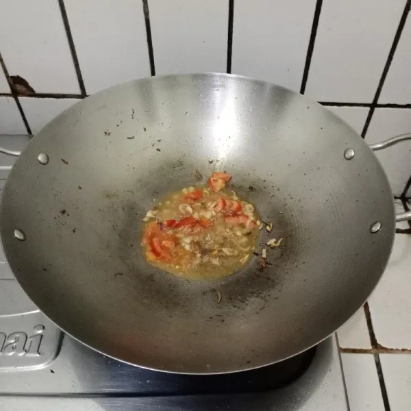 Tumis bawang merah dengan sisa minyak bekas menggoreng tahu dan ikan sampai wangi. Masukkan irisan tomat, aduk sampai layu.