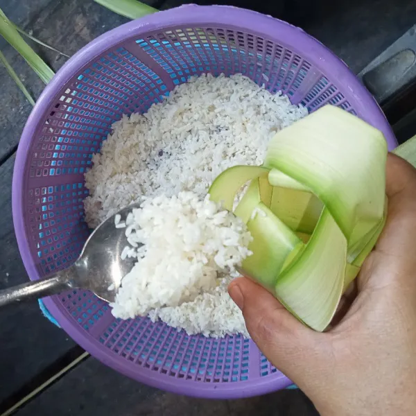 Isi cangkang ketupat dengan beras hingga setengah cangkang.