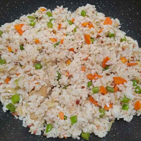 Masukkan nasi putih, aduk rata dengan tumisan. Koreksi rasa sesuai selera. Angkat dan sajikan nasi goreng dengan telur dadar rawis.