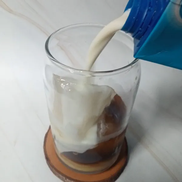 Tuang susu cair sampai setinggi 3/4 gelas.