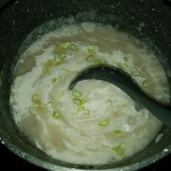 Setelah bubur benar-benar mengental, tuang santan dan masukkan daun bawang. Masak terus sambil diaduk.