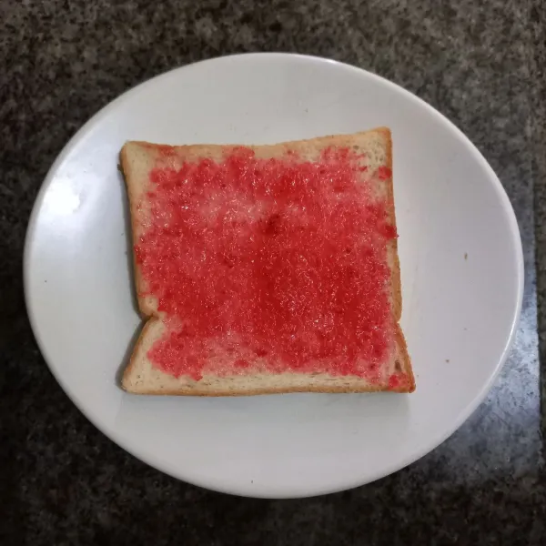 Olesi permukaan roti tawar dengan selai strawberry, ratakan.