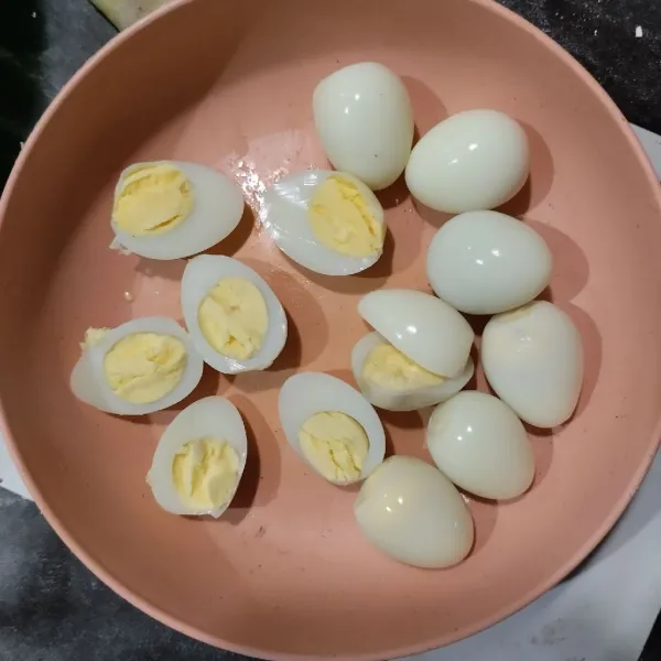 Kupas telur puyuh rebus, belah jadi 4 bagian.