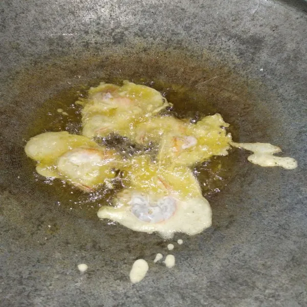 Masukkan udang ke dalam adonan tepung, lalu goreng hingga matang.