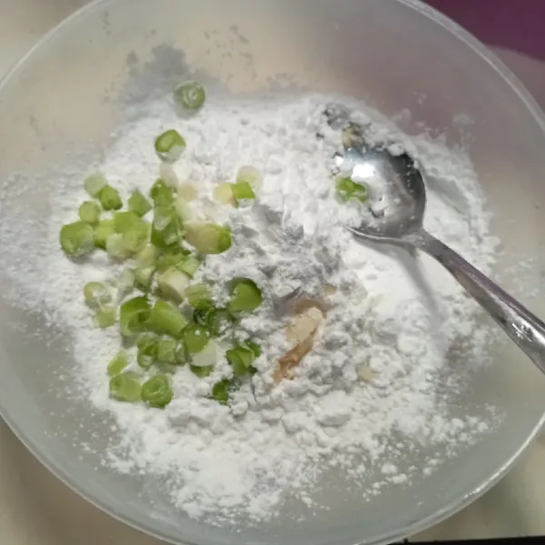 Masukkan tepung tapioka, tepung terigu, irisan daun bawang, garam dan kaldu bubuk ke dalam wadah