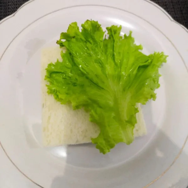 Langkah yang pertama siapkan roti tawar tambahkan sayur selada yang sudah dicuci bersih.
