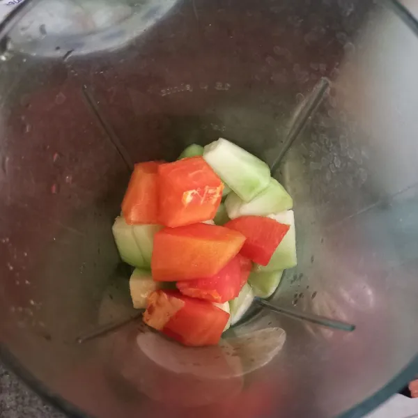 Masukkan potongan buah pepaya, melon dan air ke dalam blender, haluskan.