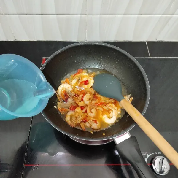 Lalu masukkan cabai besar merah, cabai rawit, air, kaldu bubuk, dan garam. Aduk rata. Masak hingga mendidih.