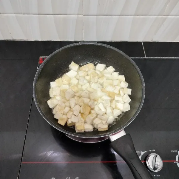 Potong dadu tahu, lalu goreng hingga berkulit. Angkat dan tiriskan.