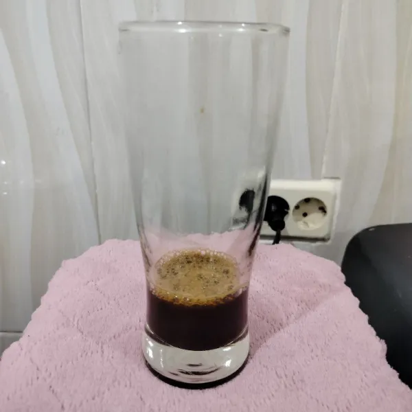 Masukkan kopi ke dalam gelas. Lalu tuang air panas mendidih dan aduk hingga rata.