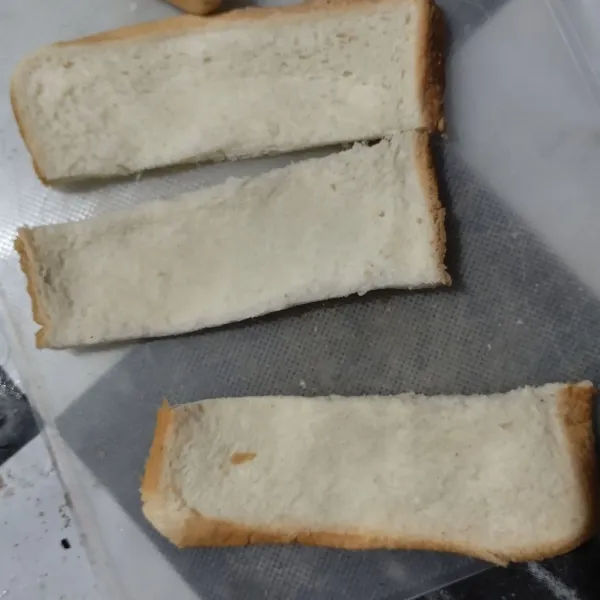 Potong selembar roti tawar menjadi 3 bagian, lalu pipihkan dengan ulekan.
