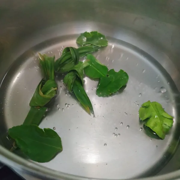 Didihkan 100 ml air, sobek ujung daun jeruk lalu masukkan ke dalam panci. Simpulkan daun pandan, lalu masukkan juga ke dalam panci.