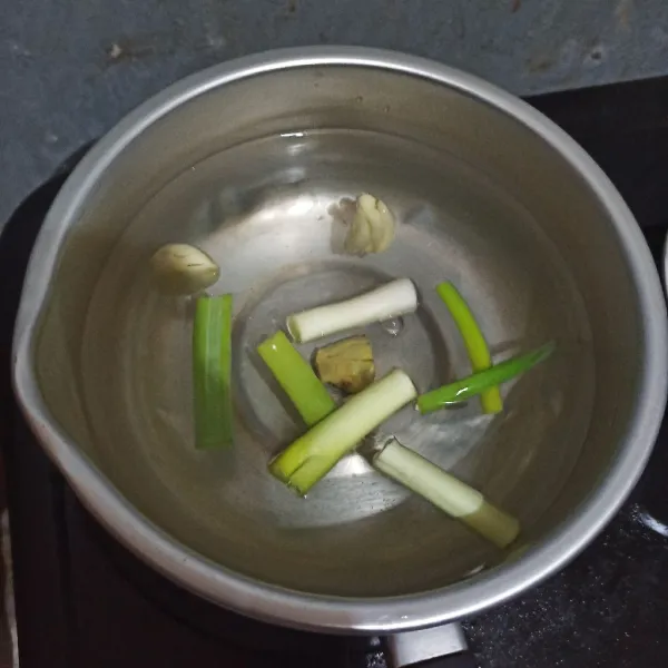 Masukkan air ke panci, beri daun prei yang sudah diiris, jahe dan bawang putih.