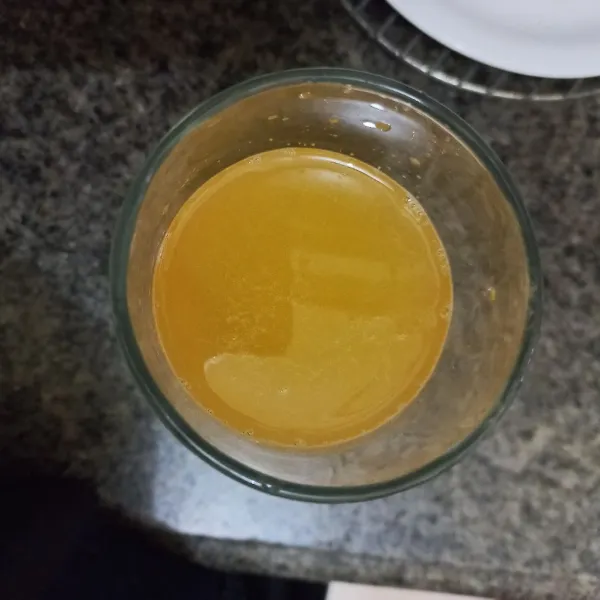 Tuang perasan jeruk pada gelas, aduk rata.