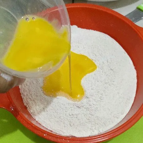 Masukkan telur ayam ke dalam campuran tepung.