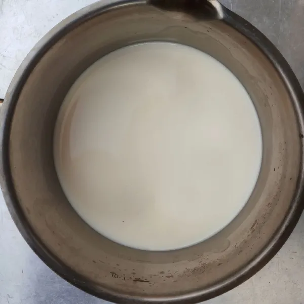 Membuat diplomat cream : Siapkan panci, tuang susu dan vanilla essence, aduk rata. Masak dengan api kecil hingga susu panas, angkat.