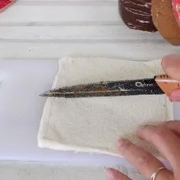 Siapkan roti tawar, pipihkan dengan rolling pin lalu bagi tiap lembarnya jadi 2 bagian, sisihkan.