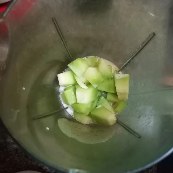 Masukkan potongan buah melon beserta susu cair ke dalam blender, haluskan.