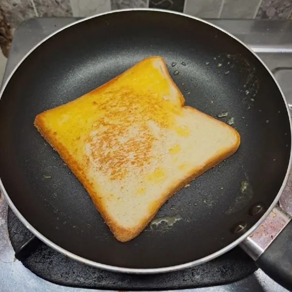 Panggang kedua roti tawar dengan sedikit margarin sampai agak kecokelatan. Angkat dan letakkan di atas piring.