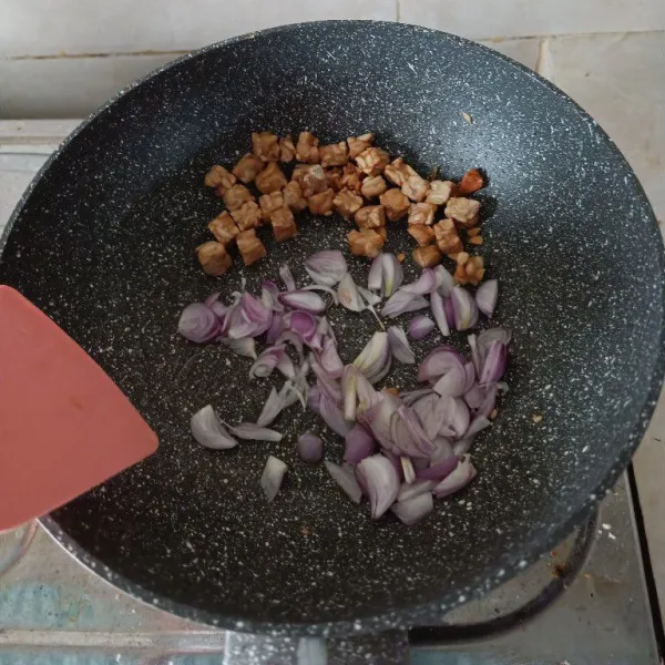 Panaskan minyak, goreng tempe sampai kecoklatan, lalu pinggirkan. Masukkan bawang merah, tumis hingga wangi.