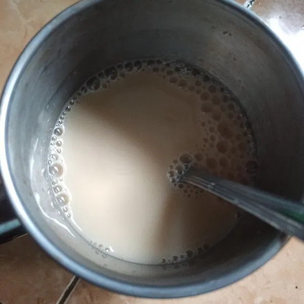 Tuang susu kental manis ke dalam gelas kemudian tambahkan air teh, aduk rata.