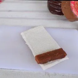 Potong-potong kue keranjang. Ambil 1 lembar roti tawar yang sudah dipipihkan lalu letakkan sepotong kue keranjang di bagian ujungnya, gulung.