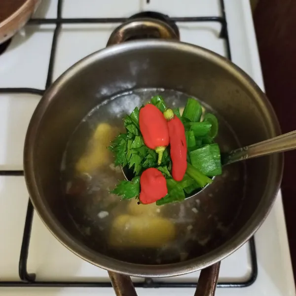 Masukkan irisan daun bawang, seledri dan cabe rawit utuh, masak hingga matang.
