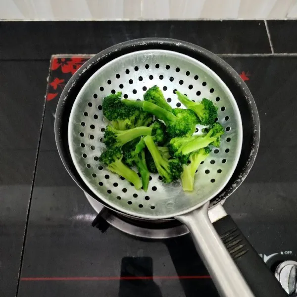 Potong brokoli per kuntum. Lalu rebus sebentar dalam air mendidih hingga berubah warna. Kemudian tiriskan brokoli dan buang air rebusannya.