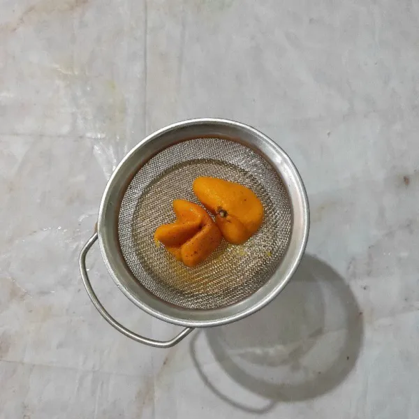 Siapkan gelas saji, lalu peras jeruk, saring.