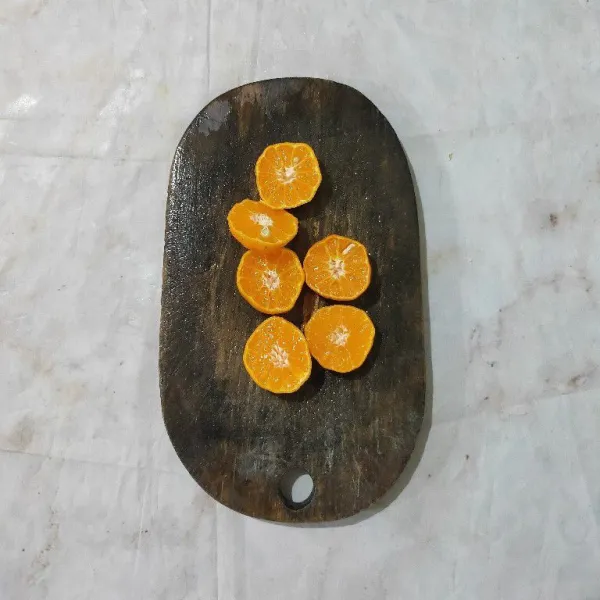 Cuci bersih jeruk, lalu belah dua.