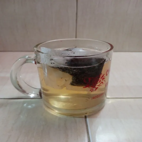 Masukkan air gula ke dalam gelas yang sudah diberi teh celup.