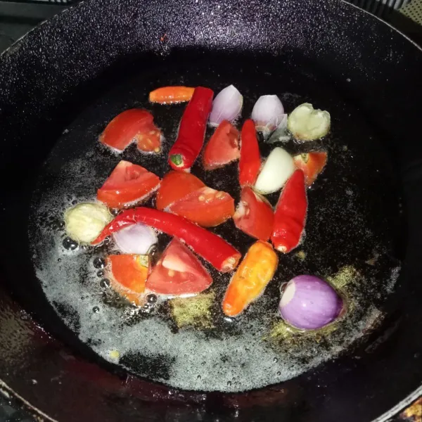 Goreng cabai, tomat, kemiri, bawang merah dan bawang putih sampai layu.